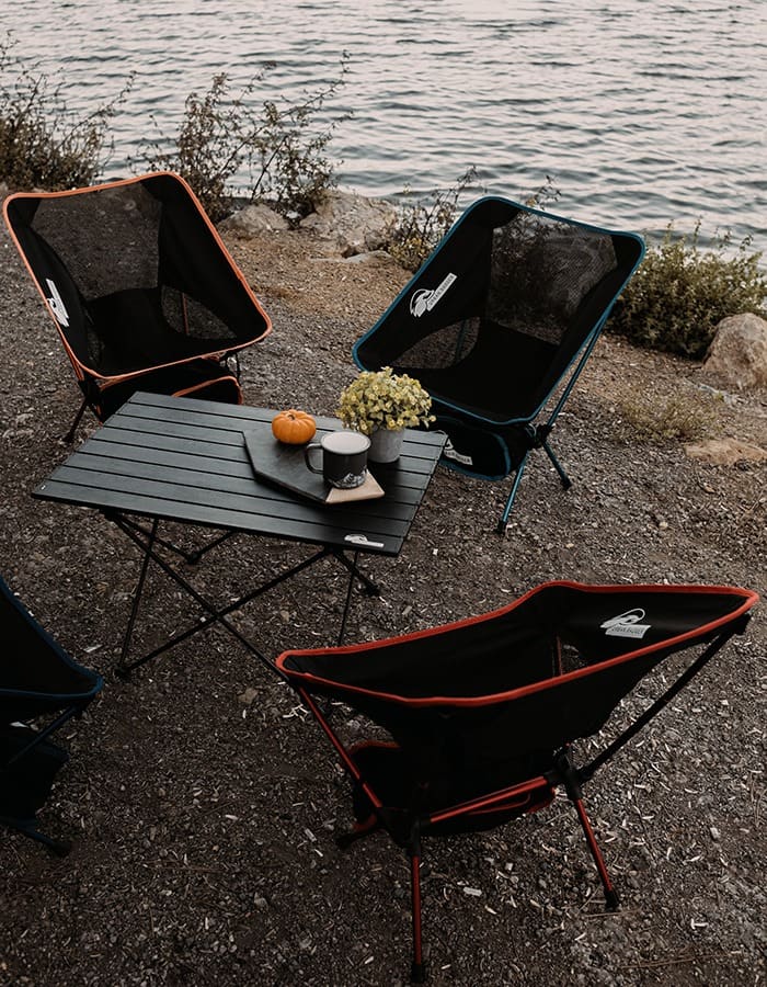 Two Loki chairs beside a small camp table on a rocky lakeshore