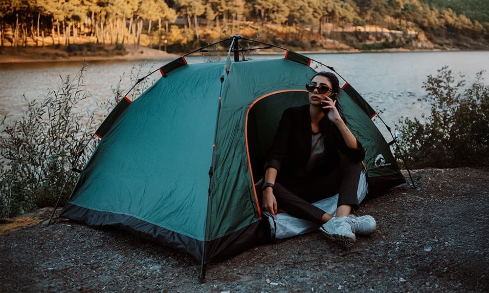 Woman sitting in the Midgard tent doorway by a lake