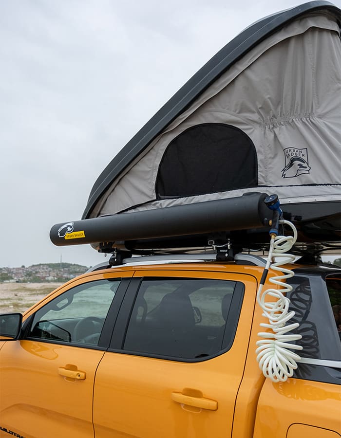 Solar shower tank and coiled hose on the roof rack, right under the roof top tent window