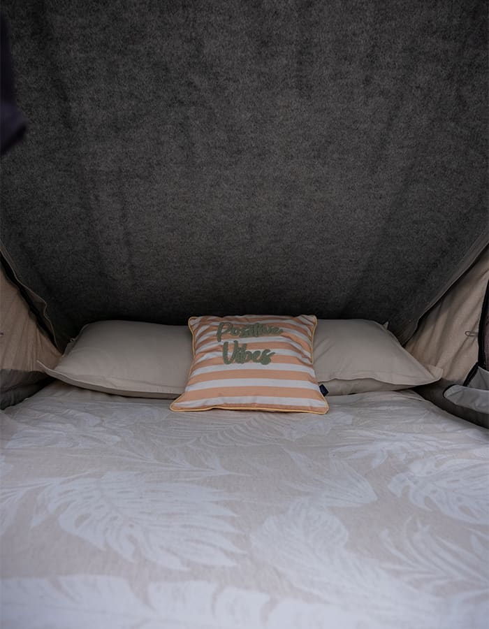 Inside the roof top tent: the mattress made up with cushions under the grey canopy