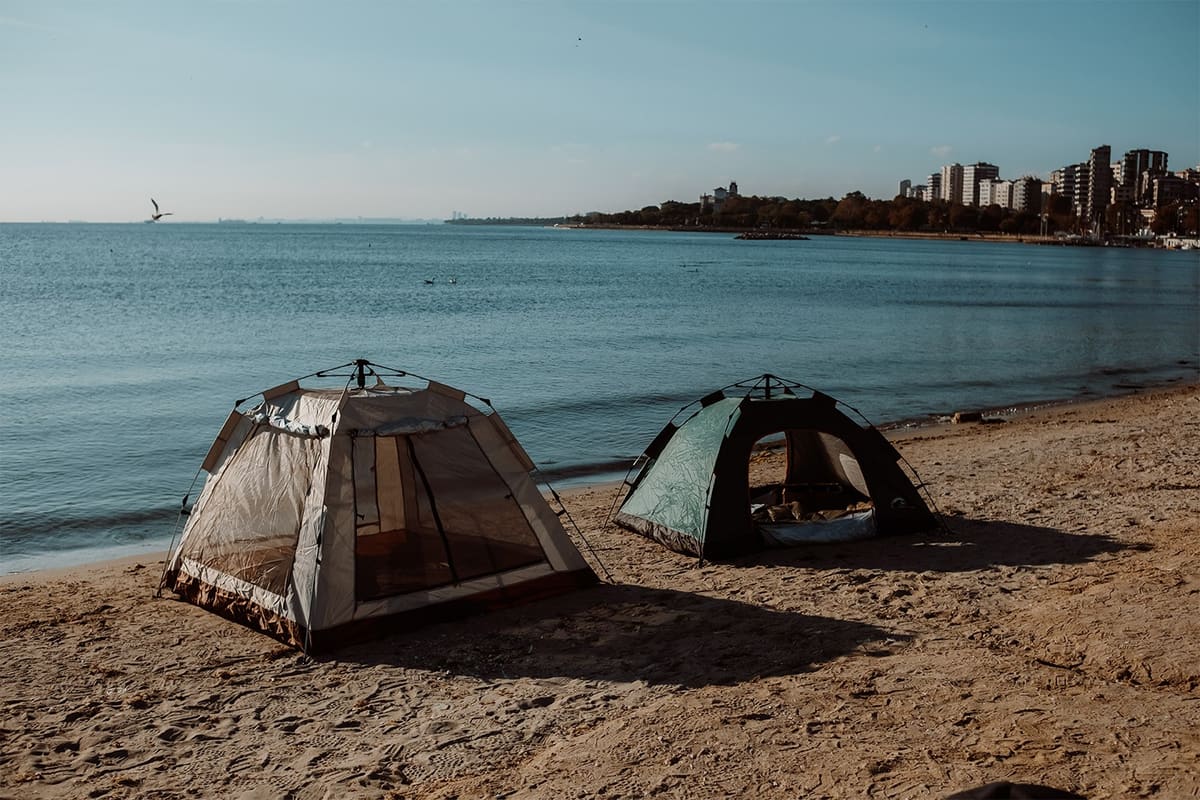 Two Urban Badger tents on a beach with the city skyline across the water